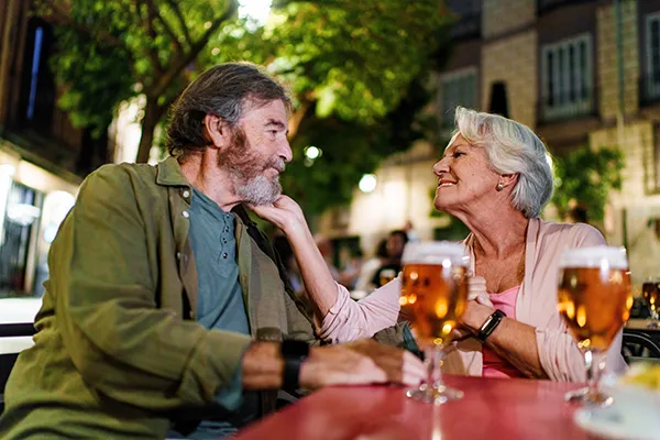 Older couple smiling at each other during date night on restaurant patio outside