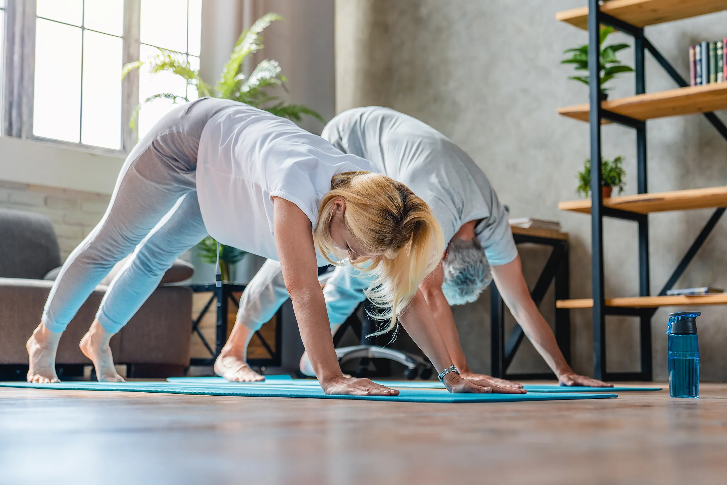 Middle aged man and woman doing yoga together in living room