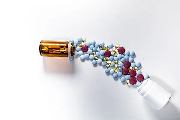 Collage of pills flowing between two open medication bottles
