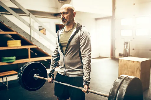 older man lifting barbell in the gym